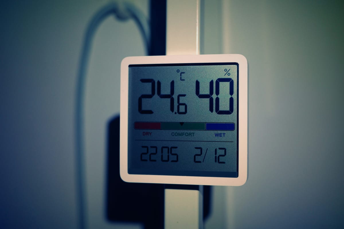 A wall-mounted digital sensor displaying room temperature and humidity readings