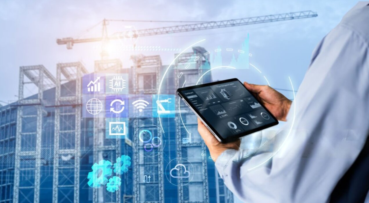 An engineer monitoring live site data on a tablet, with connected-system icons overlaid on a construction site